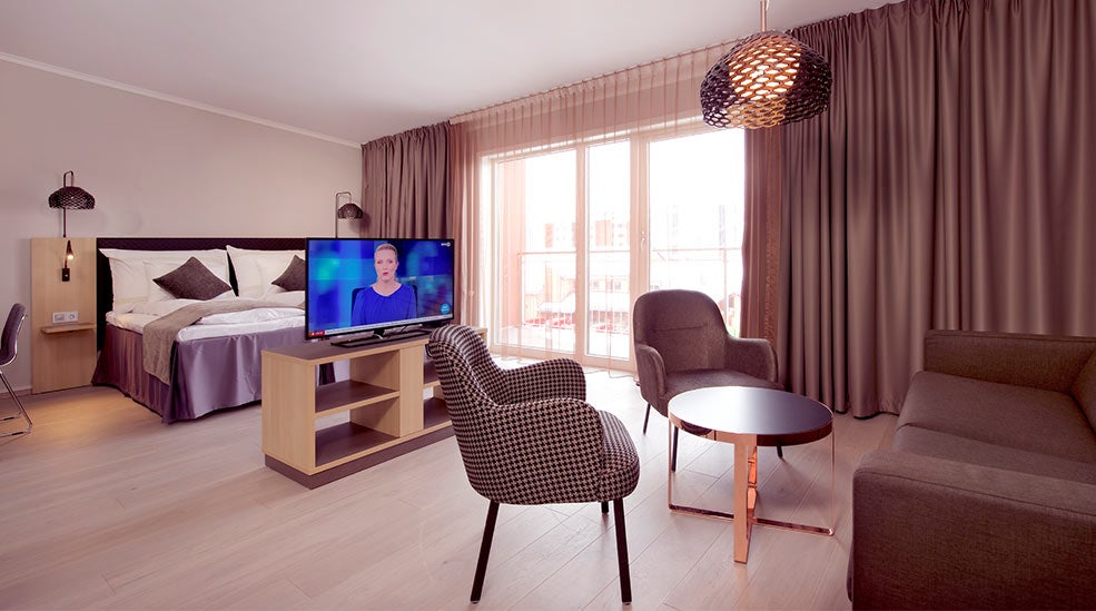 Deluxe double room with a bed, TV, lounge area and windows at the Clarion Collection Hotel Hammer