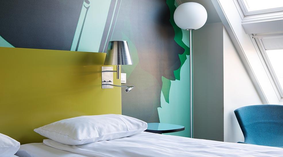 Bed with pillows, a lamp and armchair in a standard double room at the Comfort Hotel Kristiansand