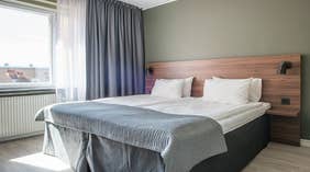 Standard double room with double bed, window and lamp at Quality Hotel Grand Kristianstad