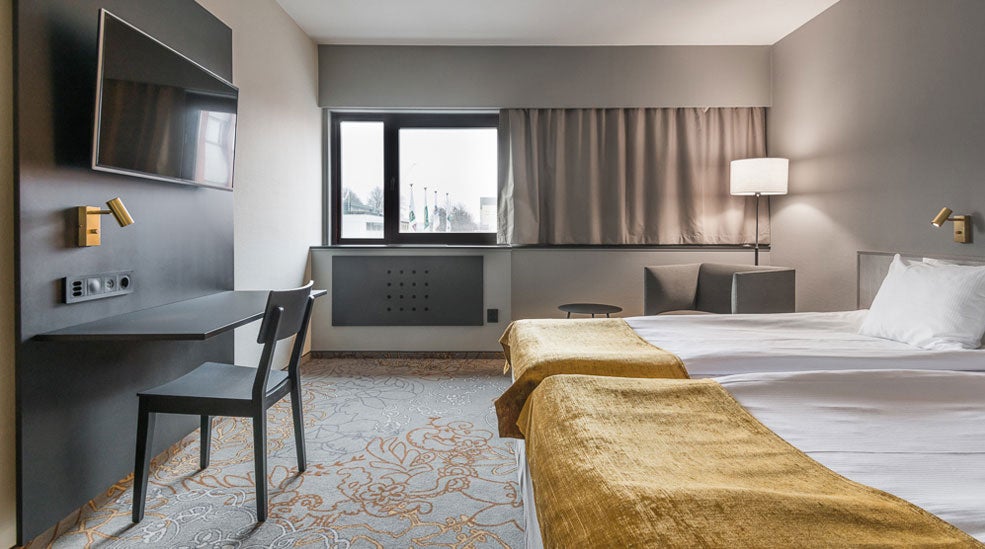 TV, desk and chair, windows and bed in a superior double room at the Quality Hotel Royal Corner